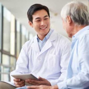 friendly smiling young asian doctor talking and explaining test result to elderly patient in hospital